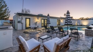 A modern outdoor patio with lounge chairs, a pool, and a dining area. - Old Town Gem by Porter | Dog-Friendly Home w/Heated Pool and Arcade Games (Scottsdale)