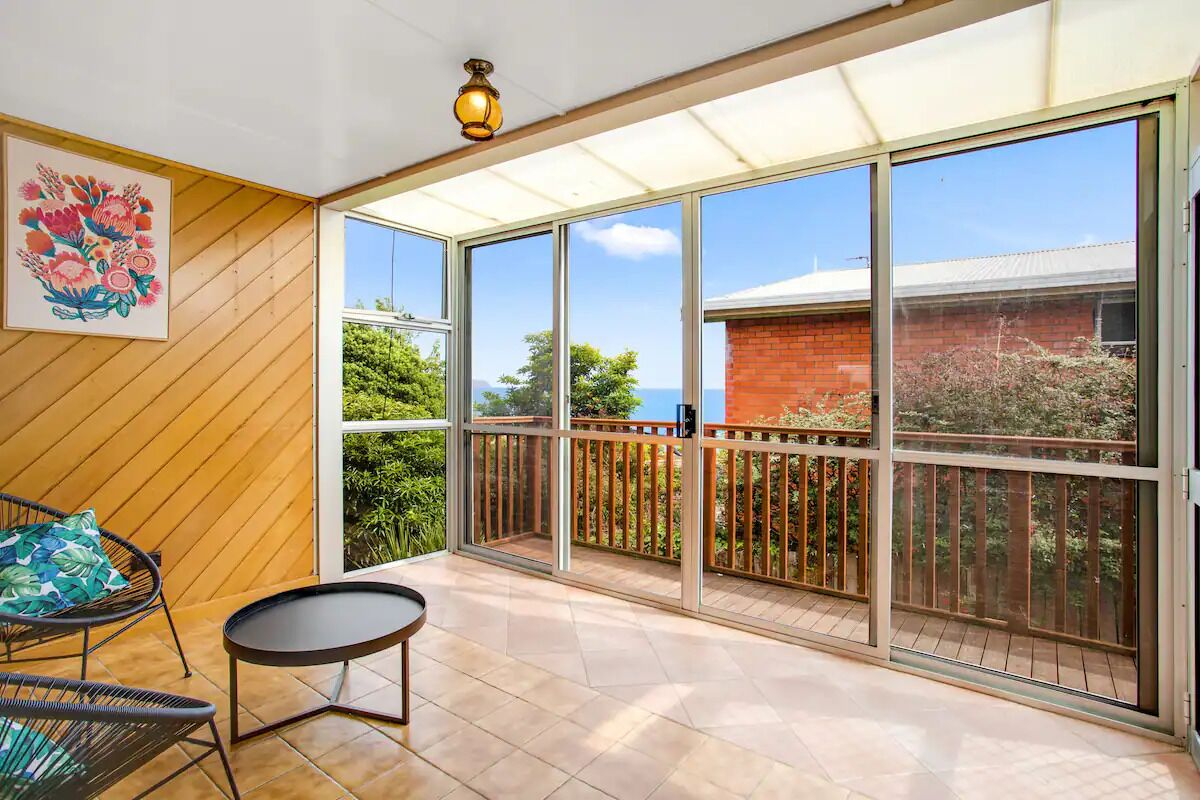 Un balcon avec vue sur la mer, un mur en bois et un tableau.