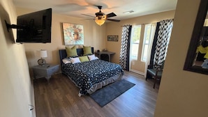 A bedroom with a bed, nightstands, a ceiling fan, a painting, and a window with curtains. - Cozy 5 bedroom/ 9 beds, 3 full baths with game room (Huntsville)