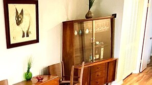 A dining area with a wooden table and chairs, a cabinet with glass doors, and a framed picture on the wall.