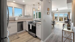 A modern kitchen with white cabinets, stainless steel appliances, and a large window. - New Listing! - 11A Mariners Walk - Ocean Front (Isle Of Palms)