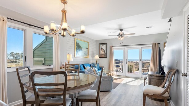 A spacious dining area with a round table and chairs, a chandelier, and a ceiling fan. - New Listing! - 11A Mariners Walk - Ocean Front (Isle Of Palms)