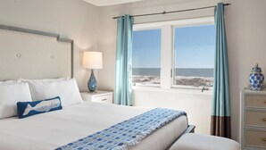 A bedroom with a large bed, a nightstand with a lamp, a dresser, and a view of the beach. - New Listing! - 11A Mariners Walk - Ocean Front (Isle Of Palms)