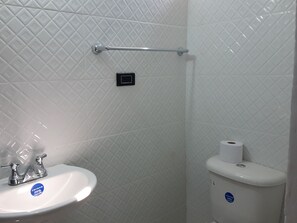 Ein Badezimmer mit Waschbecken, Toilette und Handlauf an der Wand.