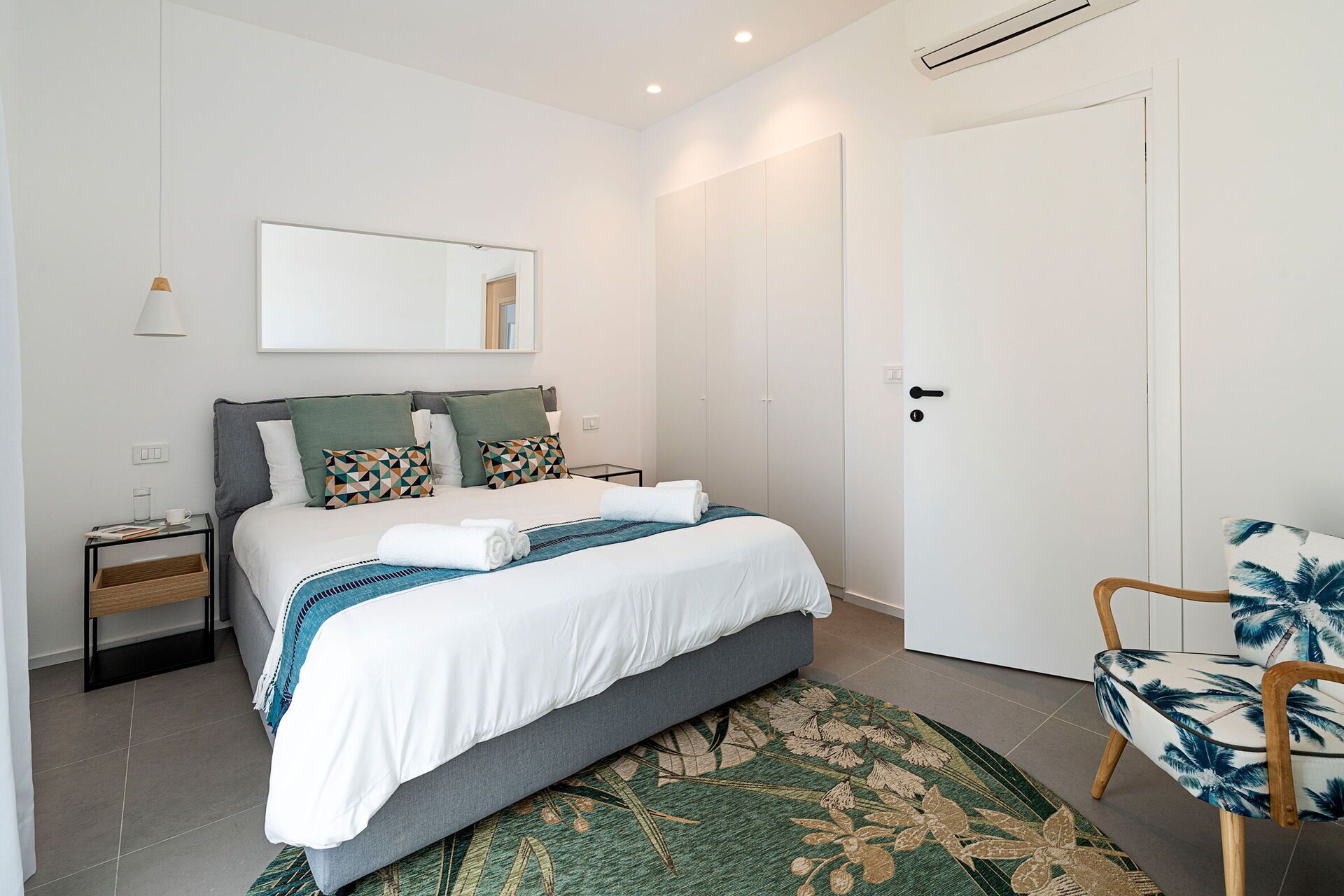 Une chambre à coucher moderne avec un lit, une table de chevet, une chaise et une porte.