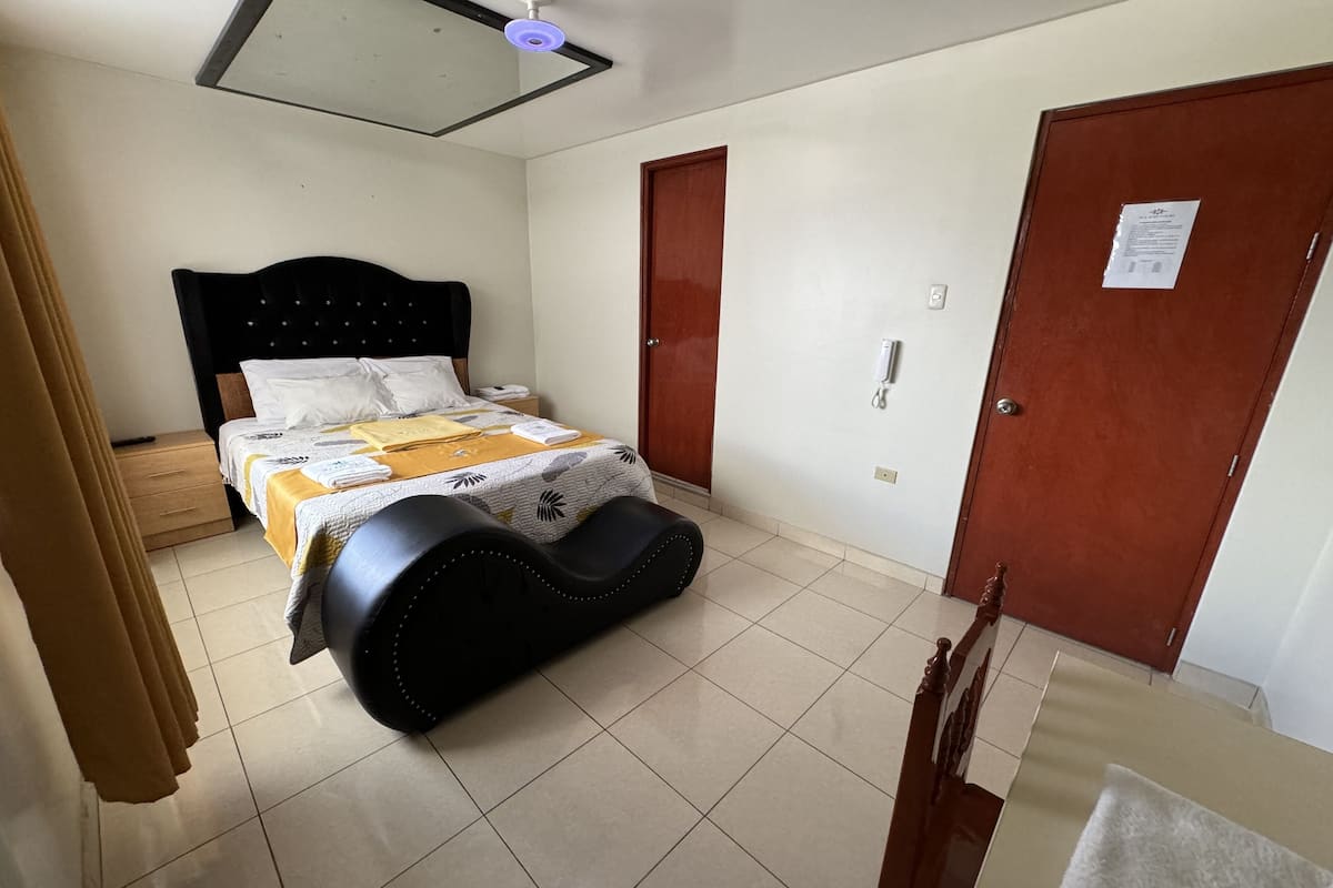Una habitación de hotel con una cama, una mesita de noche, un teléfono y una puerta.