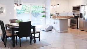Een moderne keuken met witte kasten, roestvrijstalen apparatuur en hanglampen.