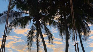 Escena de playa con palmeras y un atardecer.