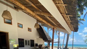 Un bar frente al mar, con sillas de mimbre y techo de paja, con vistas al océano.