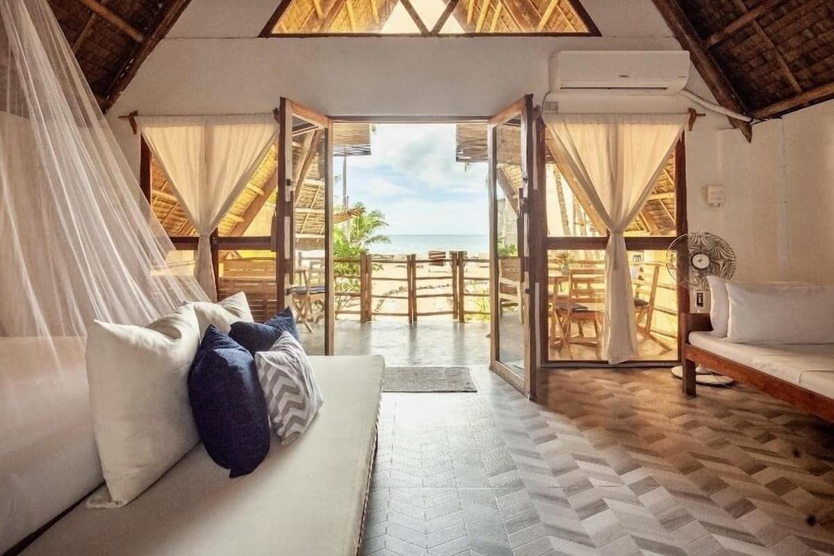 A room with a bed, a sofa, and a view of the beach.