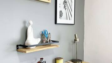 A workspace with a wooden desk, a bicycle, a lamp, and framed artwork on the wall.