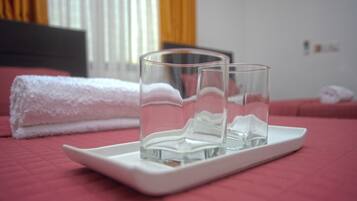 A bed with a white towel and two clear glasses on a white tray.
