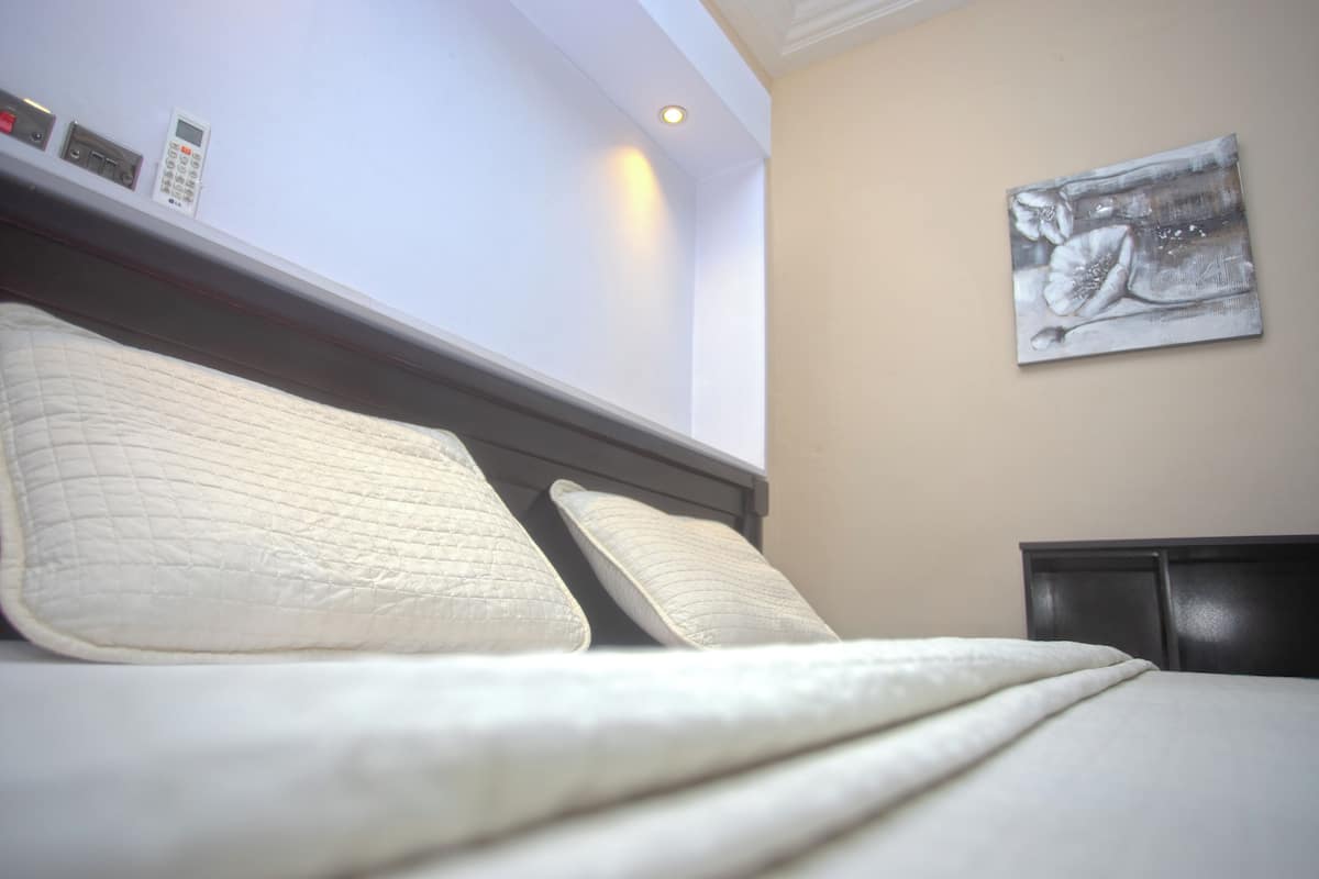A hotel room with a bed, a wall-mounted phone, and a painting.