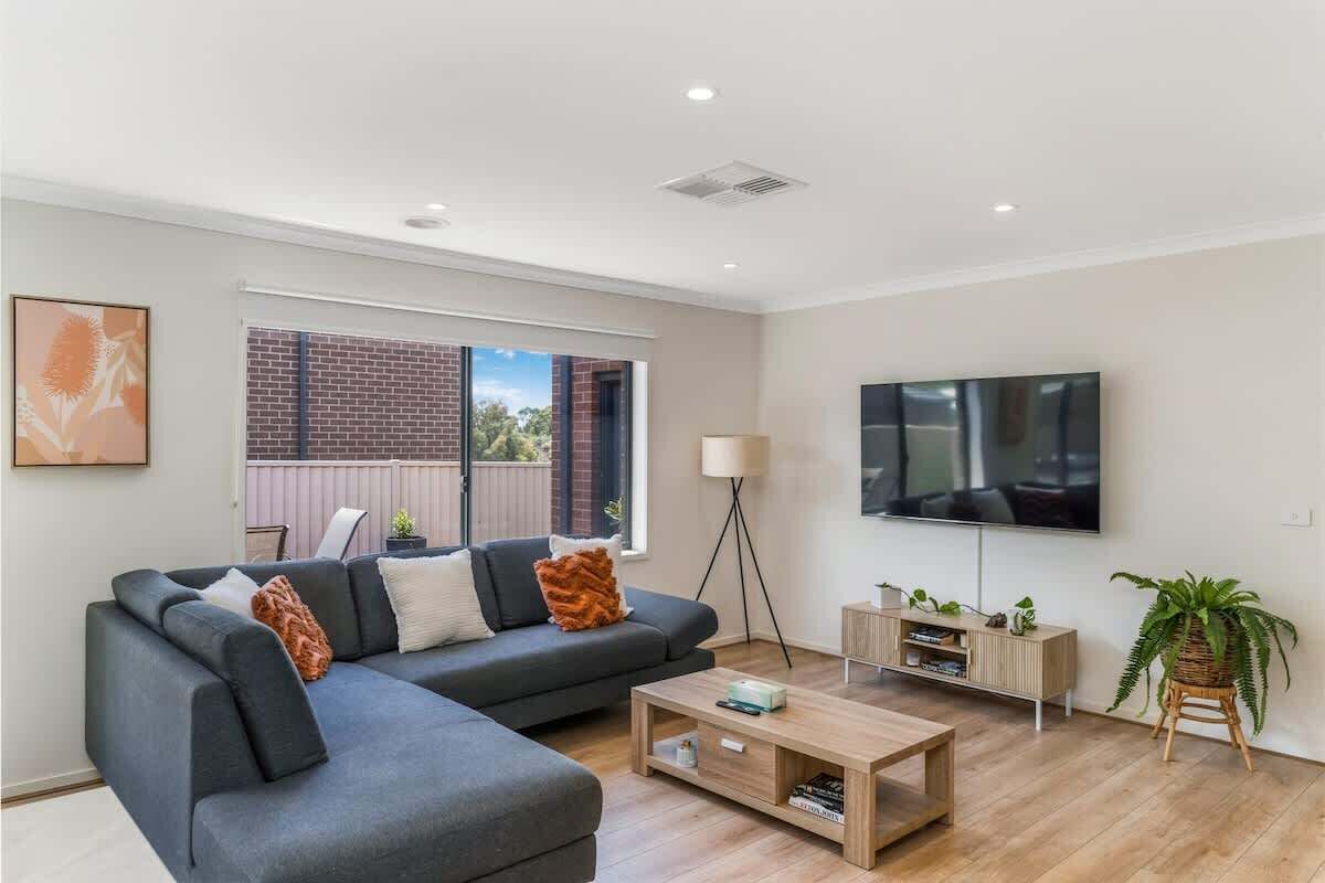 A modern living room with a sectional sofa, a coffee table, a TV, and a plant.