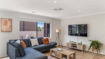 A modern living room with a sectional sofa, a coffee table, a TV, and a plant.