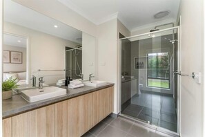 Un baño moderno con lavamanos dobles, un espejo grande y cabina de ducha con paredes de vidrio.