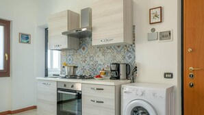 Una cocina moderna con horno empotrado, lavadora y cafetera.