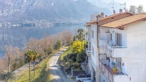 Un edificio residencial con balcón, entrada para vehículos y vistas a un lago y montañas.