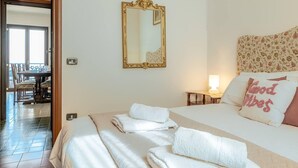 Habitación de hotel con cama, espejo, mesita de noche con lámpara y cabecera estampada con motivos florales.