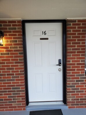 A white door with the number 16, a mailbox, and a small light fixture on the left. - Lighthouse Lodge (Pocahontas)