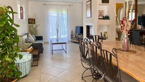 Un salon spacieux comprenant un canapé, une table à manger et des chaises, une cheminée et un téléviseur.