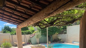 Un patio couvert avec une piscine, un espace salon extérieur et un jardin.