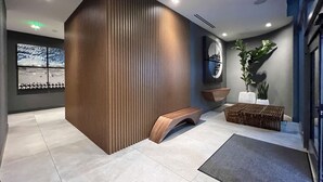 Un espace d’accueil moderne avec un mur d’accent en bois, une grande fenêtre offrant une belle vue, un comptoir d’accueil et une plante en pot.