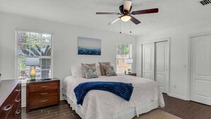 A bedroom with a bed, a nightstand, a dresser, a ceiling fan, and a window with blinds. - Summer Available! Private Pool, Private Home 6min walk to the Beach! (Panama City Beach)