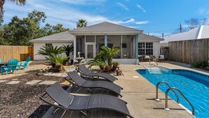 A backyard with a swimming pool, lounge chairs, and a covered patio area. - Summer Available! Private Pool, Private Home 6min walk to the Beach! (Panama City Beach)