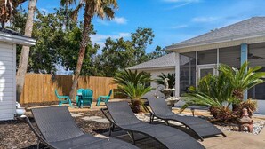 A backyard with three lounge chairs, a wooden fence, and tropical plants. - Summer Available! Private Pool, Private Home 6min walk to the Beach! (Panama City Beach)