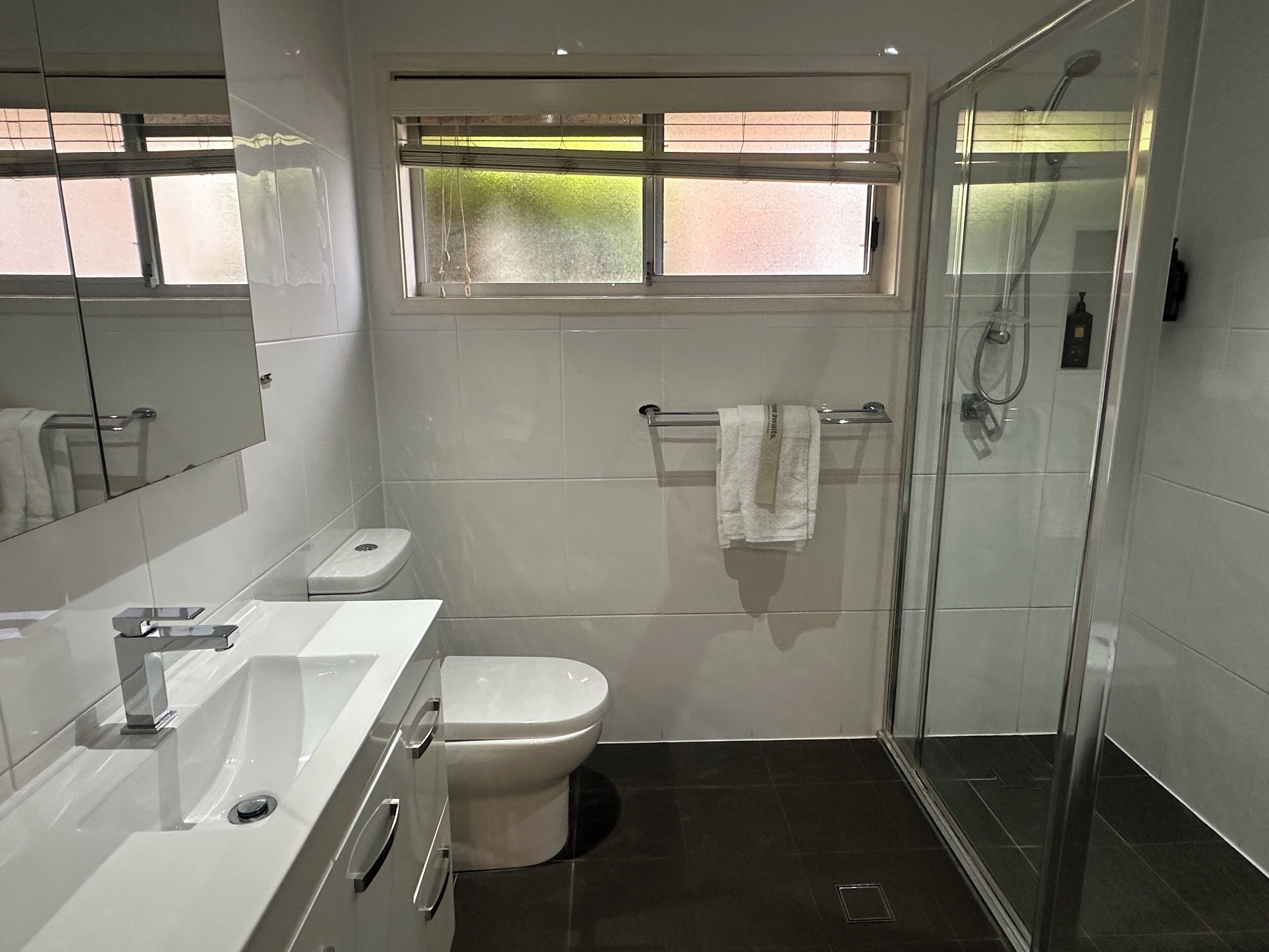 A modern bathroom with a white sink, toilet, and shower.