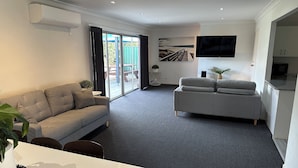 A modern living room with a grey sofa, a white table with a plant, and a grey carpet.