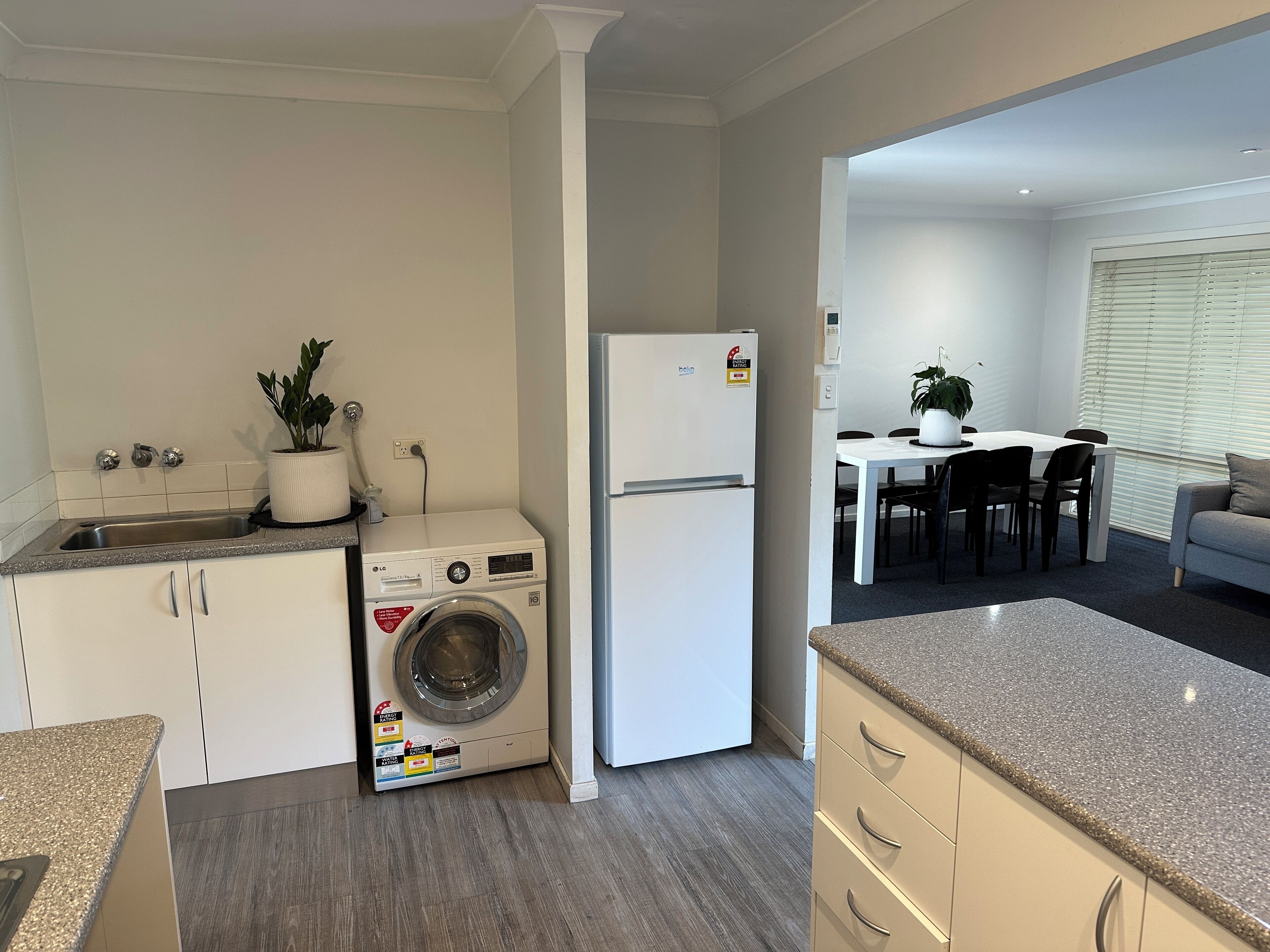 Cocina compacta con lavadora, refrigerador y comedor con mesa y sillas.