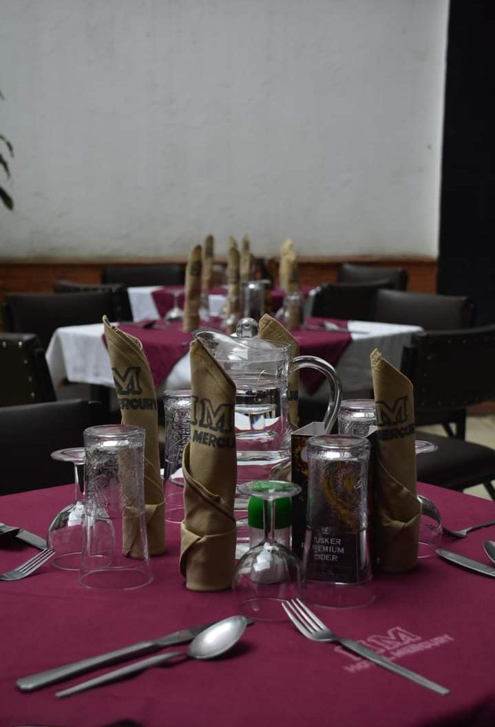 A dining table set with clear glasses, folded napkins, and cutlery.