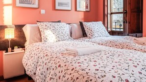 Un dormitorio con dos camas, una mesita de noche, una lámpara y cuadros en la pared.