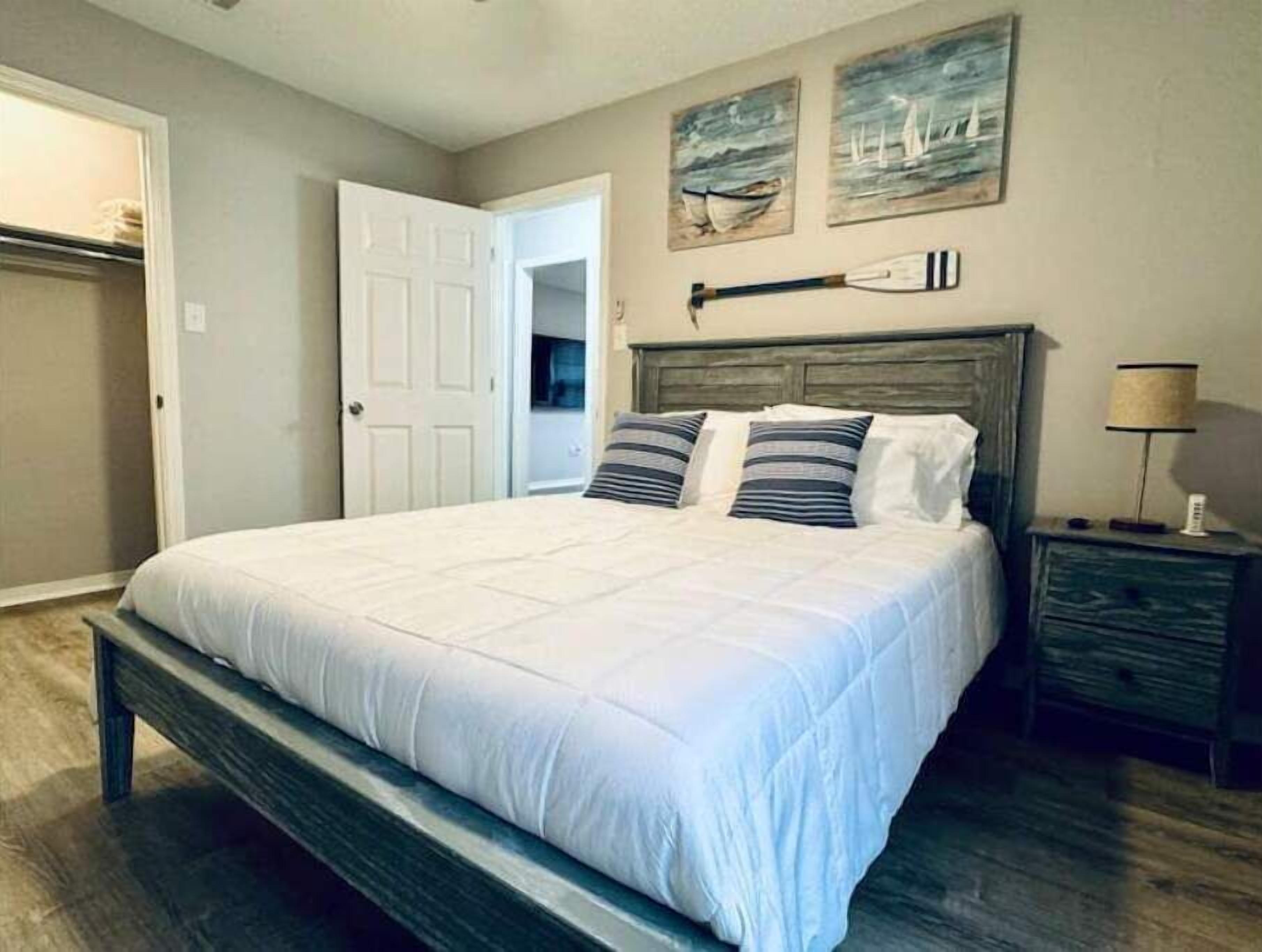 Une chambre à coucher avec un grand lit, une tête de lit en bois et une table de chevet avec une lampe.