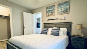 A bedroom with a large bed, a wooden headboard, and a nightstand with a lamp.