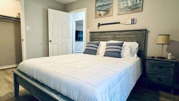 A bedroom with a large bed, a wooden headboard, and a nightstand with a lamp.