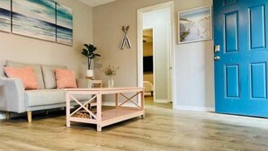 A living room with a light-colored sofa, a wooden coffee table, and a blue door.