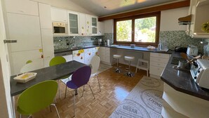 A kitchen with a dining area, wooden flooring, and a window with a view.