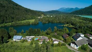 Una propietat a la vora d'un llac amb diverses cases, una piscina i un paisatge forestal.