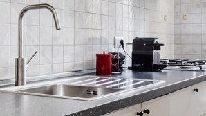 A modern kitchen with white cabinets, a stainless steel sink, and a black countertop.