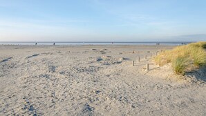 En sandstrand med fodaftryk, en klar himmel og en fjern horisont.