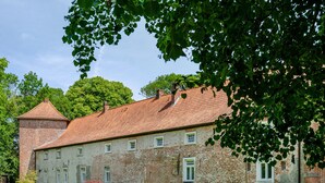 En historisk bygning med murstensfacade, mange vinduer og rødt tegltag.