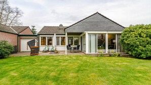 Et hus med en overdækket terrasse, garage og en velplejet græsplæne.