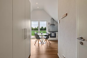 Une cuisine moderne avec un coin repas, une grande porte-fenêtre coulissante donnant sur un balcon et une vue sur la verdure.