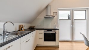 Una cucina moderna con forno integrato, lavello in acciaio inossidabile e pavimento in legno.