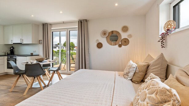 A bedroom with a bed, pillows, a bedside table, and a window.