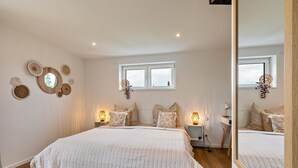 A bedroom with a large bed, bedside lamps, a window, and wall decor.