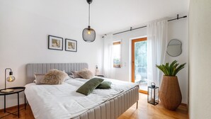 A modern bedroom with a large bed, bedside lamps, a large window with curtains, and a potted plant. - Apartment 'Casa Schneck' with Private Terrace and Wi-Fi (Longkamp)